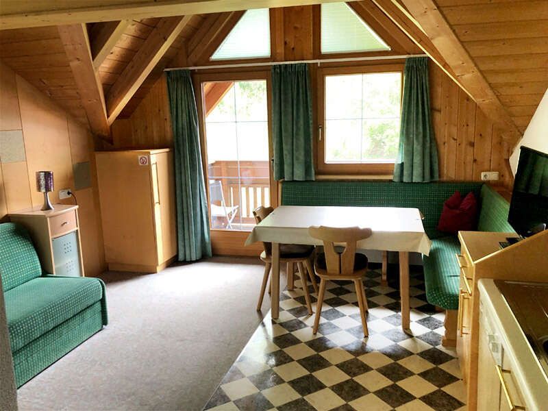 Wohnküche mit Küchenzeile, Essecke, Couch und Balkon im Appartement A